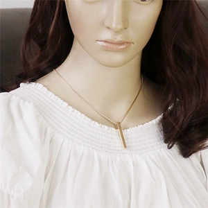 Minimalist gold bar pendant necklace with polished cylinder bar worn by a model