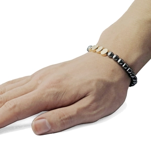 Detail of beaded bracelet with black magnetic stones and gold-plated date markers