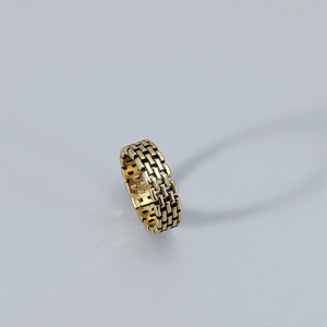 Detailed macro view of retro gold ring featuring textured brick wall pattern and vintage finish