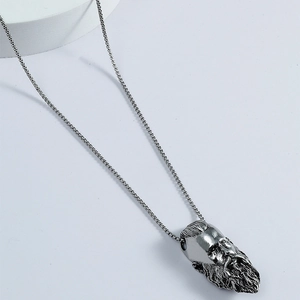 Macro shot of silver bearded man head pendant on box chain necklace with vintage texture