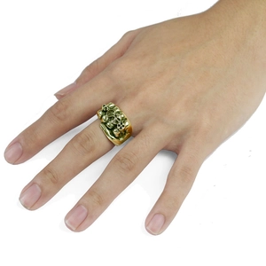 Vintage gothic fist ring with carved skulls shown on finger against white background