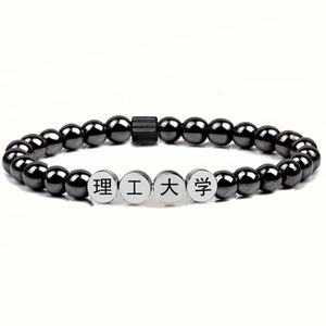 Detail view of black hematite bead bracelet with engraved silver metal charms on white background