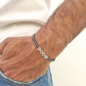 Detail of hematite bead bracelet featuring silver charms engraved with the year 1986