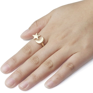 Close-up of golden star and moon open ring worn on finger with adjustable band
