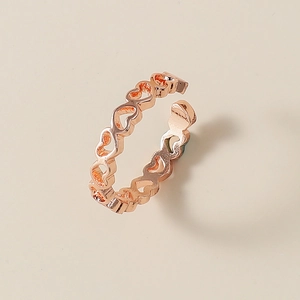 Dettaglio dei cuori traforati collegati su un anello aperto in finitura oro rosa