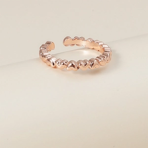 Vue détaillée de la bague ajustable en forme de cœur en or rose sur fond minimaliste