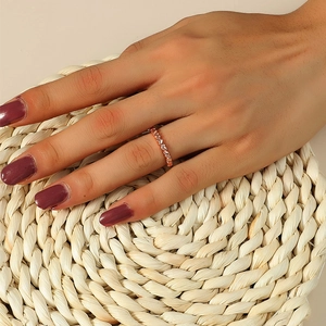 Gros plan détaillé d'une bague cœurs entrelacés en or rose portée au doigt d'une femme