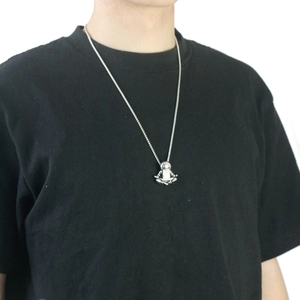 Vintage silver astronaut pendant necklace on a long chain worn over a black shirt