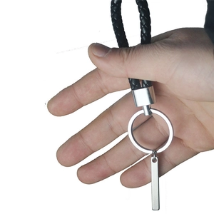Détail d'un porte-clés en cuir tressé noir avec étiquette rectangulaire en métal mat