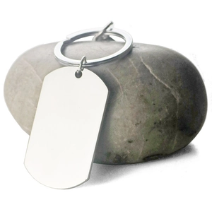 Minimalist stainless steel dog tag keychain with phone number engraving on a river stone