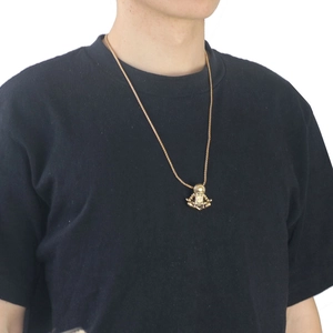 Detail of vintage gold astronaut pendant in meditation pose on woven metal chain