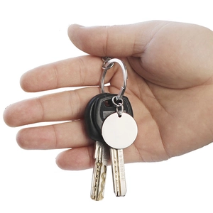 Close-up of a personalized round metal keychain with customized engraving held by hand