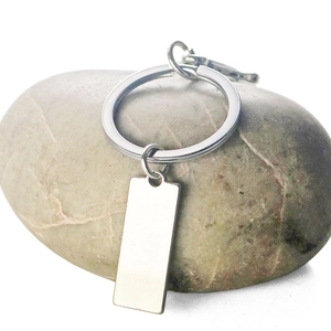 Customizable rectangular stainless steel license plate keychain on decorative white stones