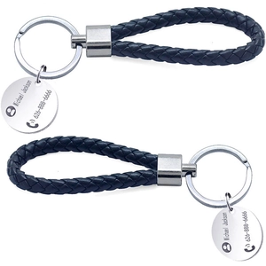 Detail of custom engraved round metal tag on a black braided leather keychain strap