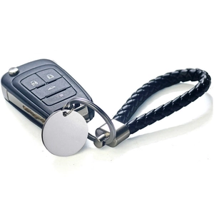Detail of a black braided leather keychain with a round metal tag for custom engraving