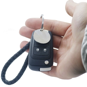 Close-up of a personalized silver round tag with black braided leather car keychain