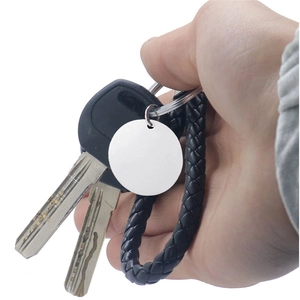 Close-up of black braided leather keychain with customizable round silver metal pendant tag