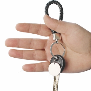 Detail of hand holding a black braided leather keychain with customizable silver metal tag