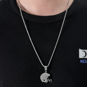 Gros plan du pendentif casque de football américain serti de strass sur une chaîne torsadée argent