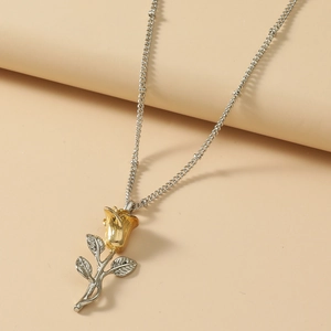 Macro shot of gold rose flower pendant with silver stem and leaves on delicate chain