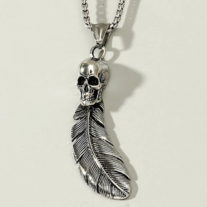 Macro view of gothic skull and feather pendant in matte silver steel for punk necklaces