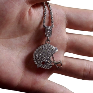 Gros plan d'un pendentif casque de rugby argenté serti de strass brillants sur chaîne