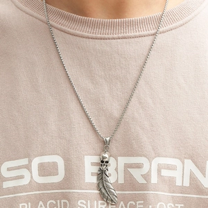 Gothic punk necklace featuring a vintage skull and feather pendant worn on a model