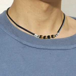 Tiger eye stone bead necklace with black leather cord for men and women worn on blue top