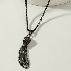 Macro shot of gothic black skull and feather pendant on a square box chain necklace
