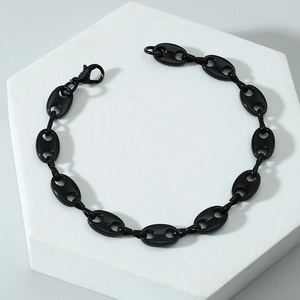 Détail d'un bracelet gourmette grain de café noir poli présenté sur un socle blanc