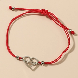 Détail d'un bracelet tressé rouge avec breloque cœur ajouré et battement de cœur
