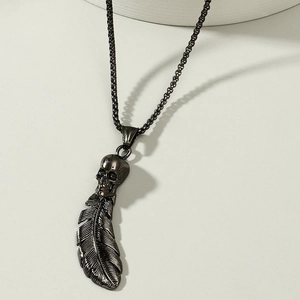 Macro shot of punk gothic skull and feather pendant on a black metal box chain