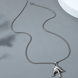 Hip hop love hand gesture pendant on silver box chain against a clean industrial background