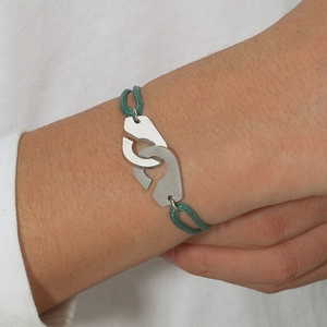 Détail du bracelet en corde tressée verte avec menottes en argent sur le poignet