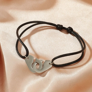 Détail du bracelet menottes réglable sur un élégant fond de tissu en soie champagne