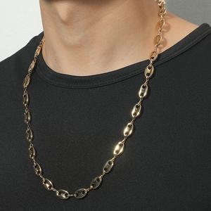 Gros plan d'un collier à mailles grains de café dorées porté sur un t-shirt noir chic