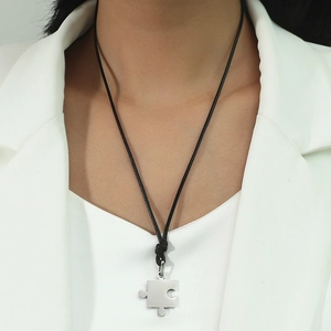 Pendentif puzzle en acier inoxydable avec cordon noir sur un modèle en costume blanc