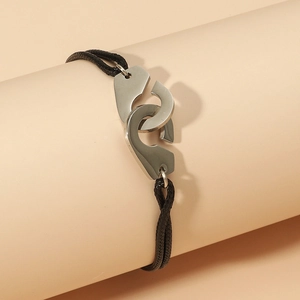 Détail du charm menottes argentées sur bracelet en corde tressée noire ajustable