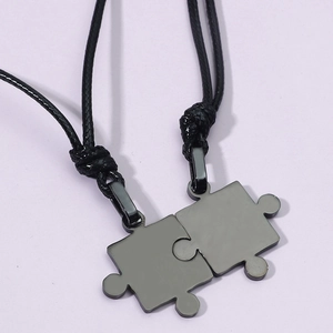 Gros plan de pendentifs puzzle emboîtables en acier noir sur cordons tressés noirs