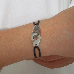 Détail d'un bracelet en corde tressée noire réglable avec menottes en acier inoxydable