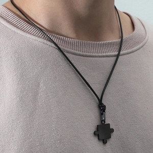 Gros plan d'un pendentif puzzle noir minimaliste avec cordon ciré sur vêtement décontracté