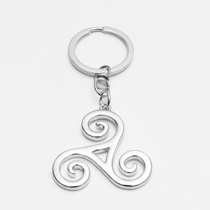 Macro detail of silver Triskele pendant with polished metallic finish on white background