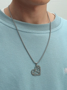 Pendentif cœur géométrique argenté poli sur chaîne porté par un modèle masculin sur du bleu