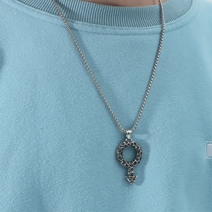 Gros plan du pendentif symbole de genre martelé vintage sur une chaîne argentée