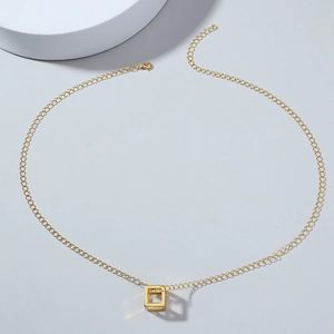 Minimalist gold hollow cube pendant necklace on a clean grey background with soft shadows