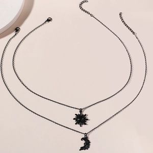 Detailed view of black layered necklaces with sun and moon pendants on beige background