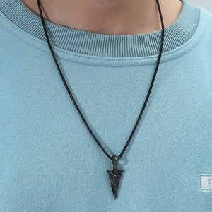 Gros plan d'un pendentif flèche noire pour homme avec détails sculptés sur chaîne
