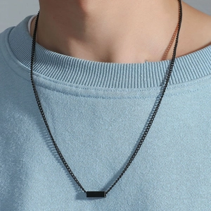 Close-up of a minimalist black rectangle pendant necklace on a blue textured sweater