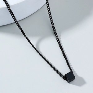 Close-up of black cube pendant on steel chain necklace with minimalist industrial design