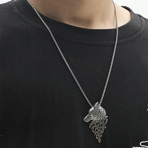 Detail shot of a silver wolf head pendant with box chain on a black knit shirt